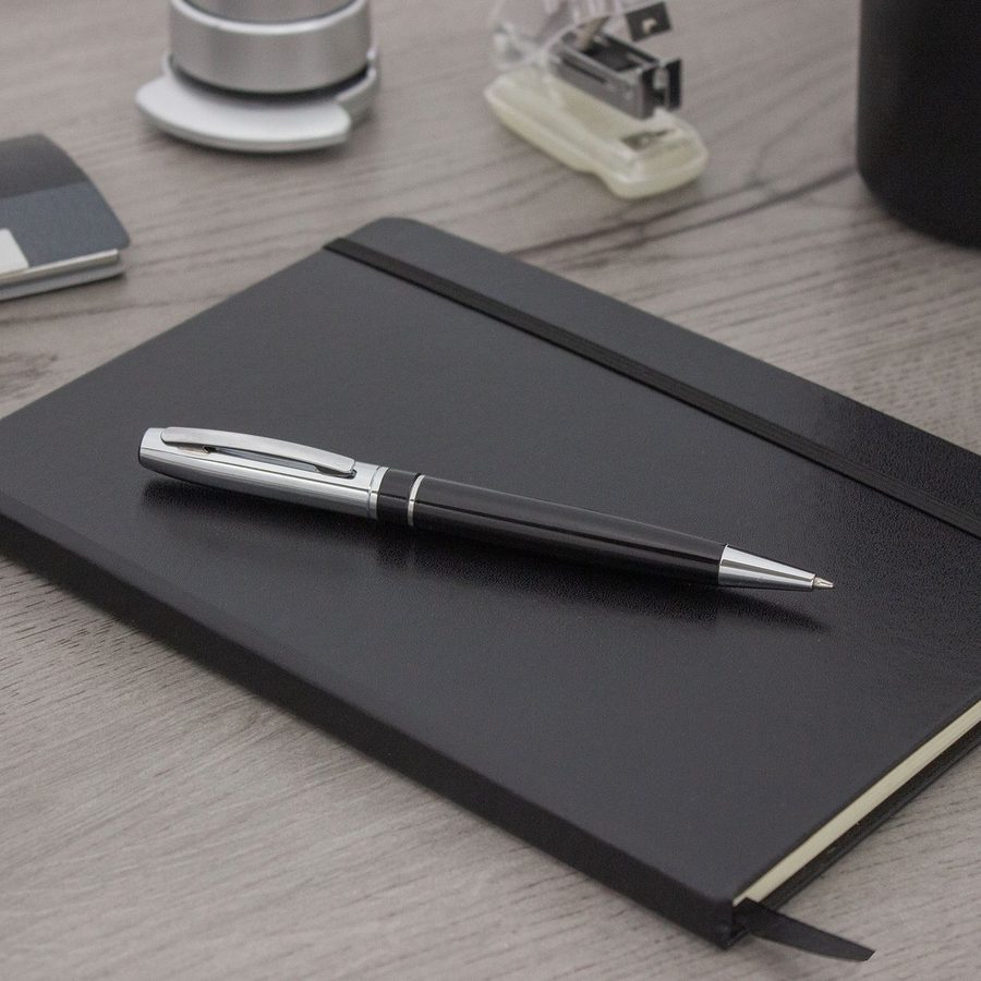 Bolígrafo metálico sobre una libreta de tapa dura negra